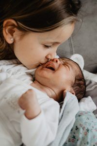 Niña besando a su hermanito recién nacido