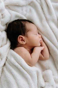 Recién nacido durmiendo de lado en una manta blanca - Reportaje newborn a domicilio en El Puerto de Santa Maria