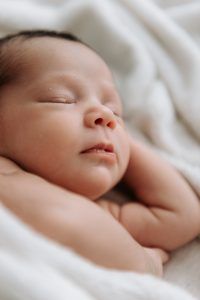 Recién nacido durmiendo de lado en una manta blanca - Reportaje newborn a domicilio en El Puerto de Santa Maria